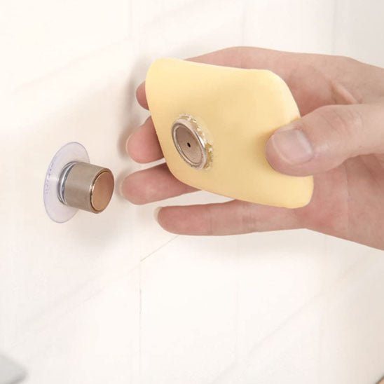 savon jaune en train d'être fixé sur porte savon aimanté